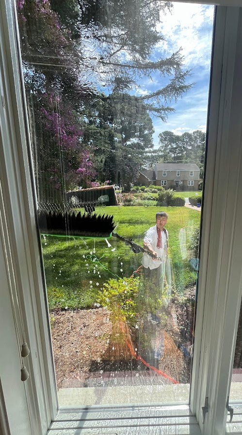 Technician cleaning an exterior window from the yard
