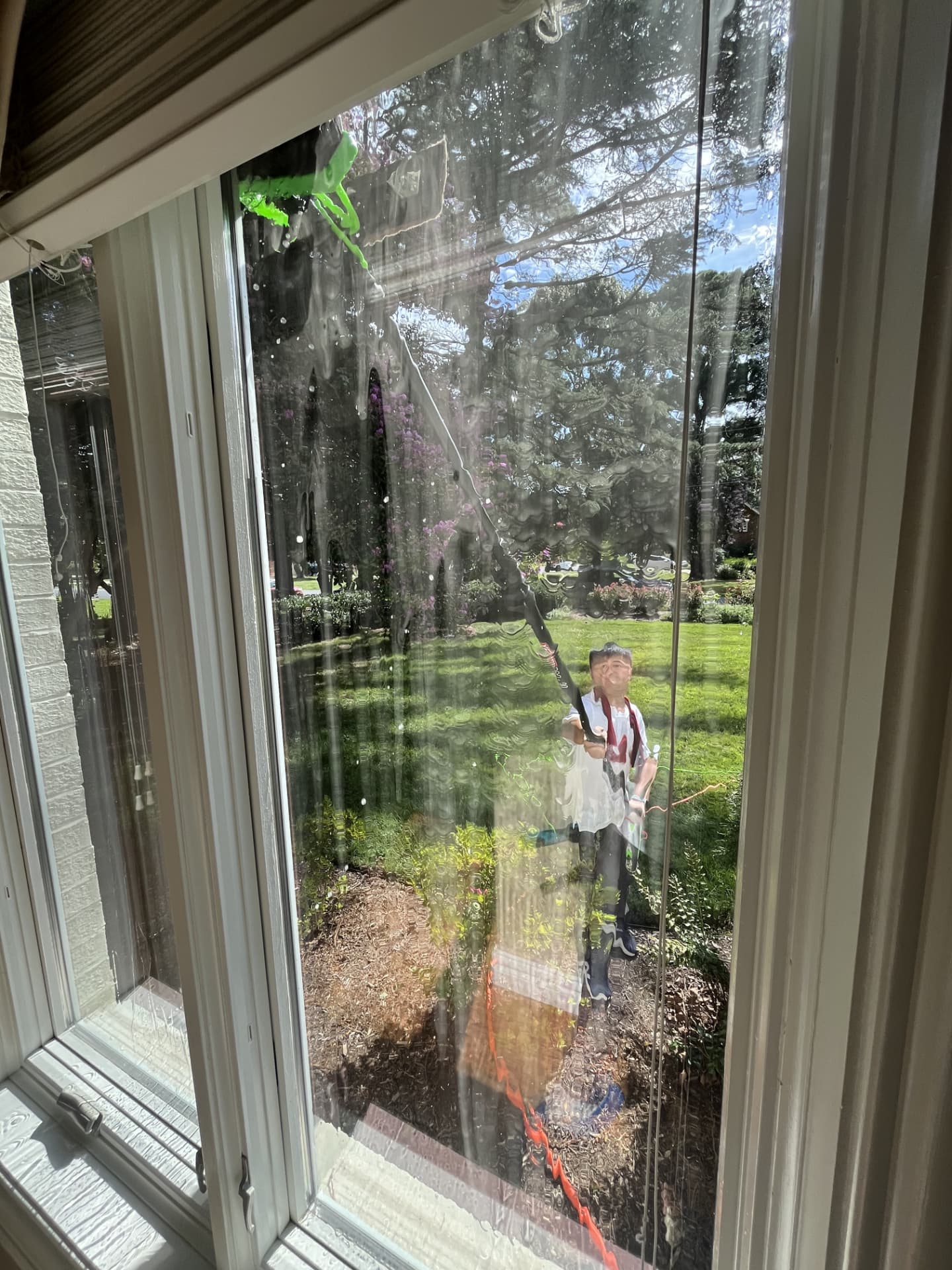 View from inside a home as a technician rinses the exterior glass with a water-fed pole